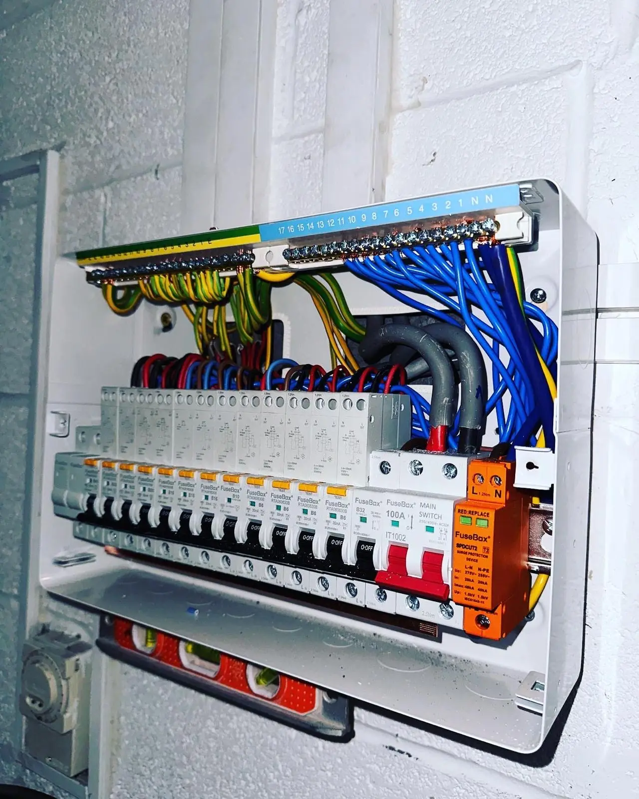 An RCBO consumer unit seen from an angle with the cover off, its surge protection device fitted and the wiring dressed neatly into the board.