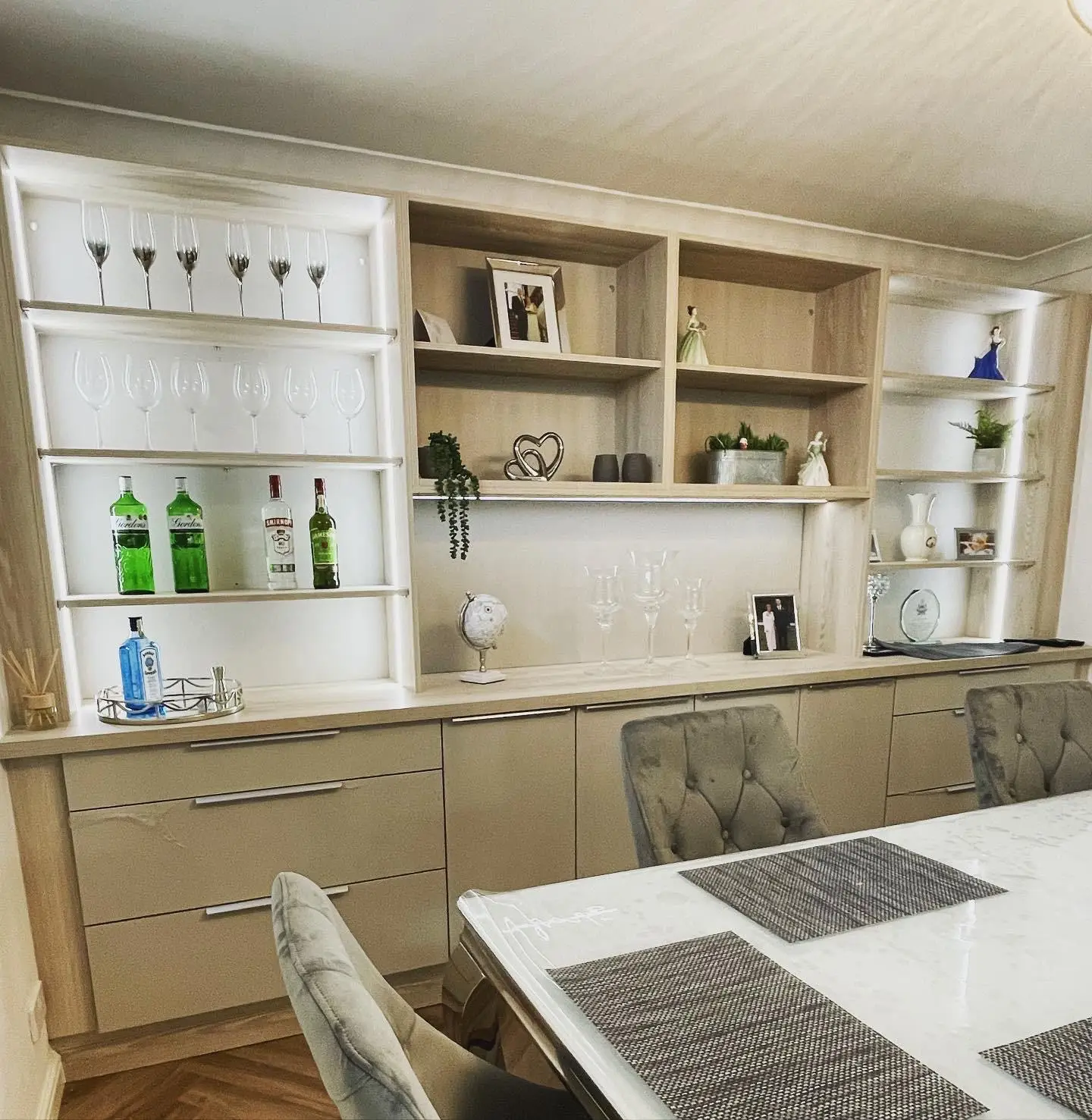 Built-in display shelving in a dining room lit by LED tape in the side channels and under the shelves.