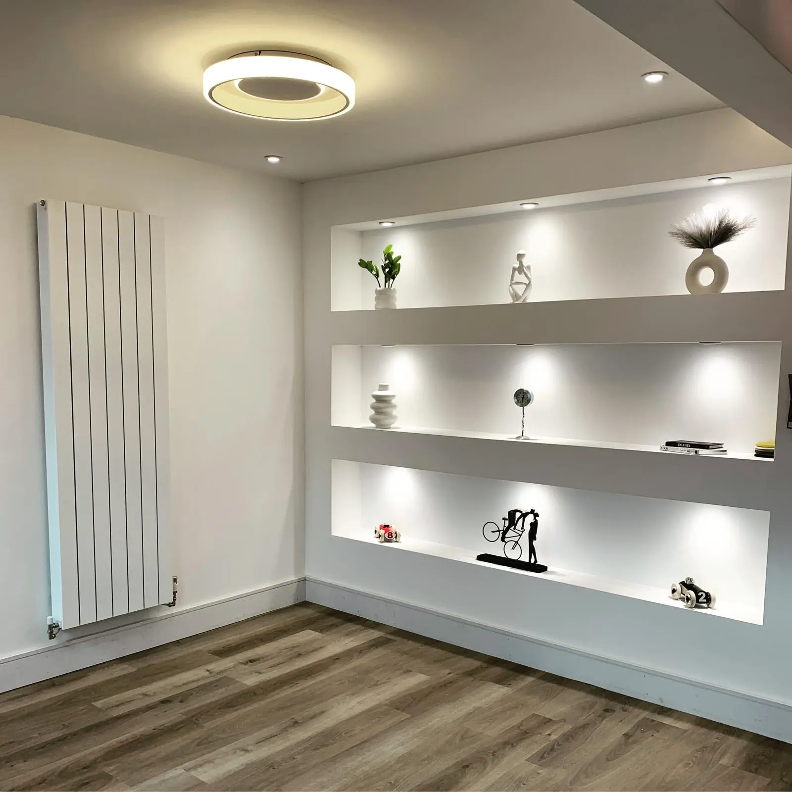 Three recessed wall shelves lit by mini recessed spotlights, with a round LED ceiling light and downlights above.