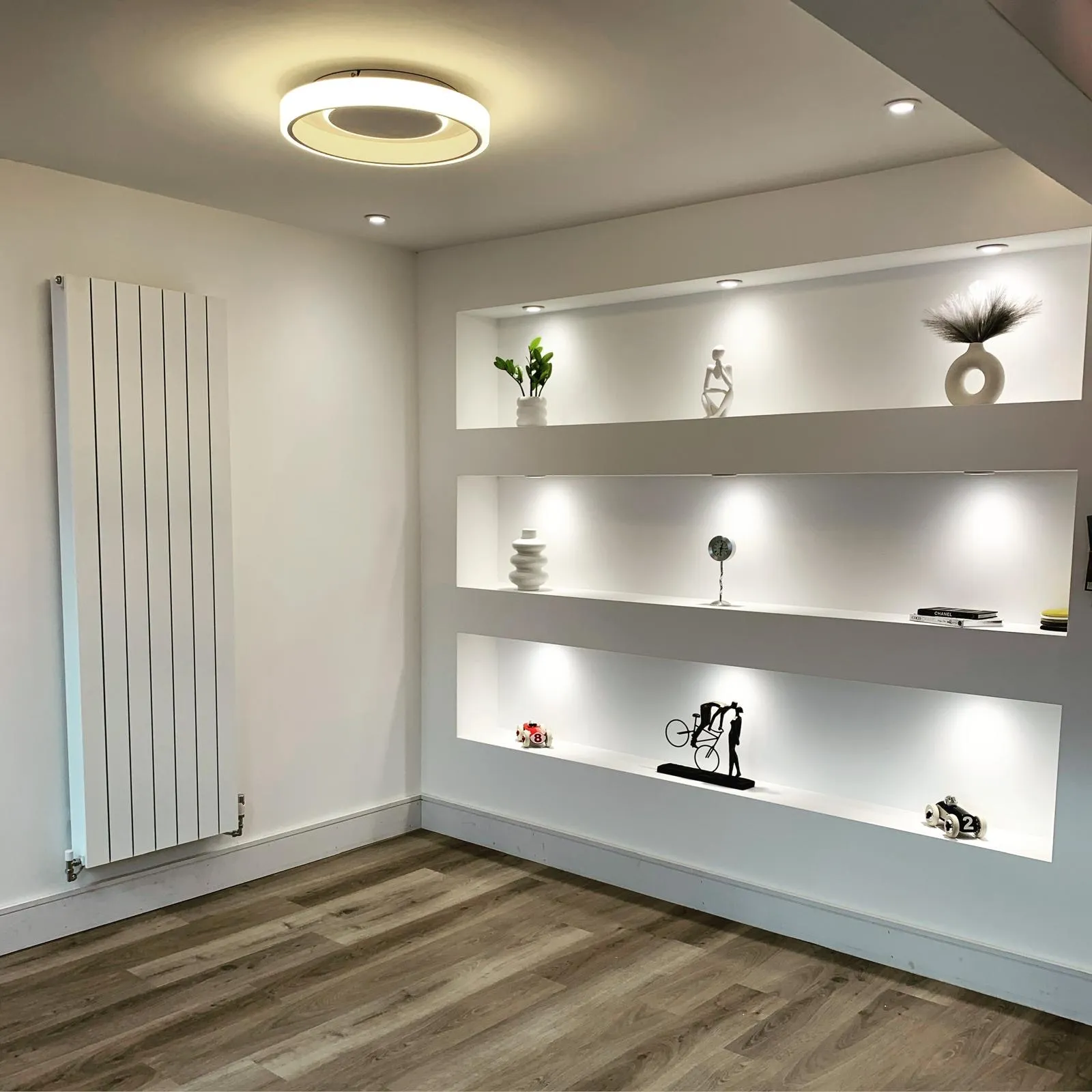 Three recessed wall shelves lit by mini recessed spotlights, with a round LED ceiling light and downlights above.