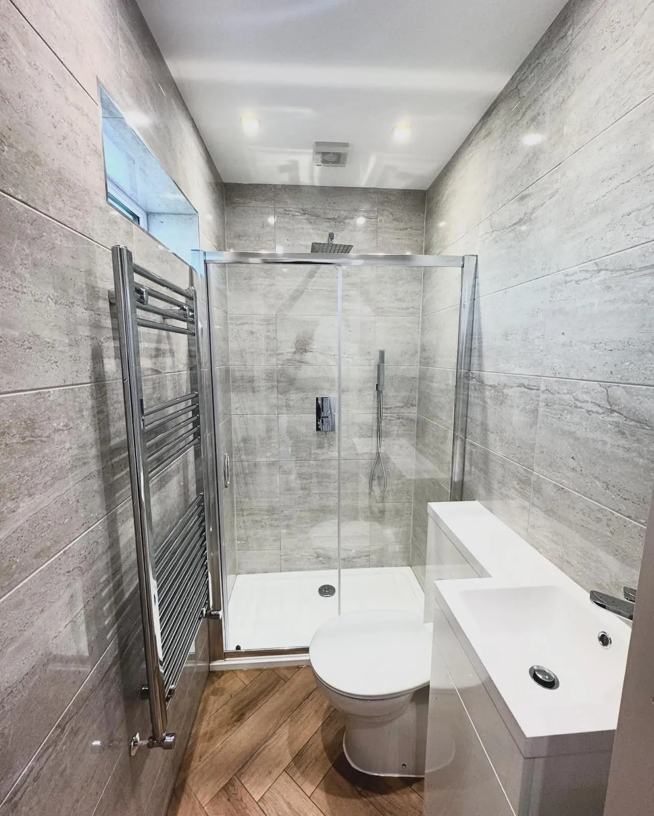 A shower room with two downlights and a ceiling extractor fan above the shower enclosure.