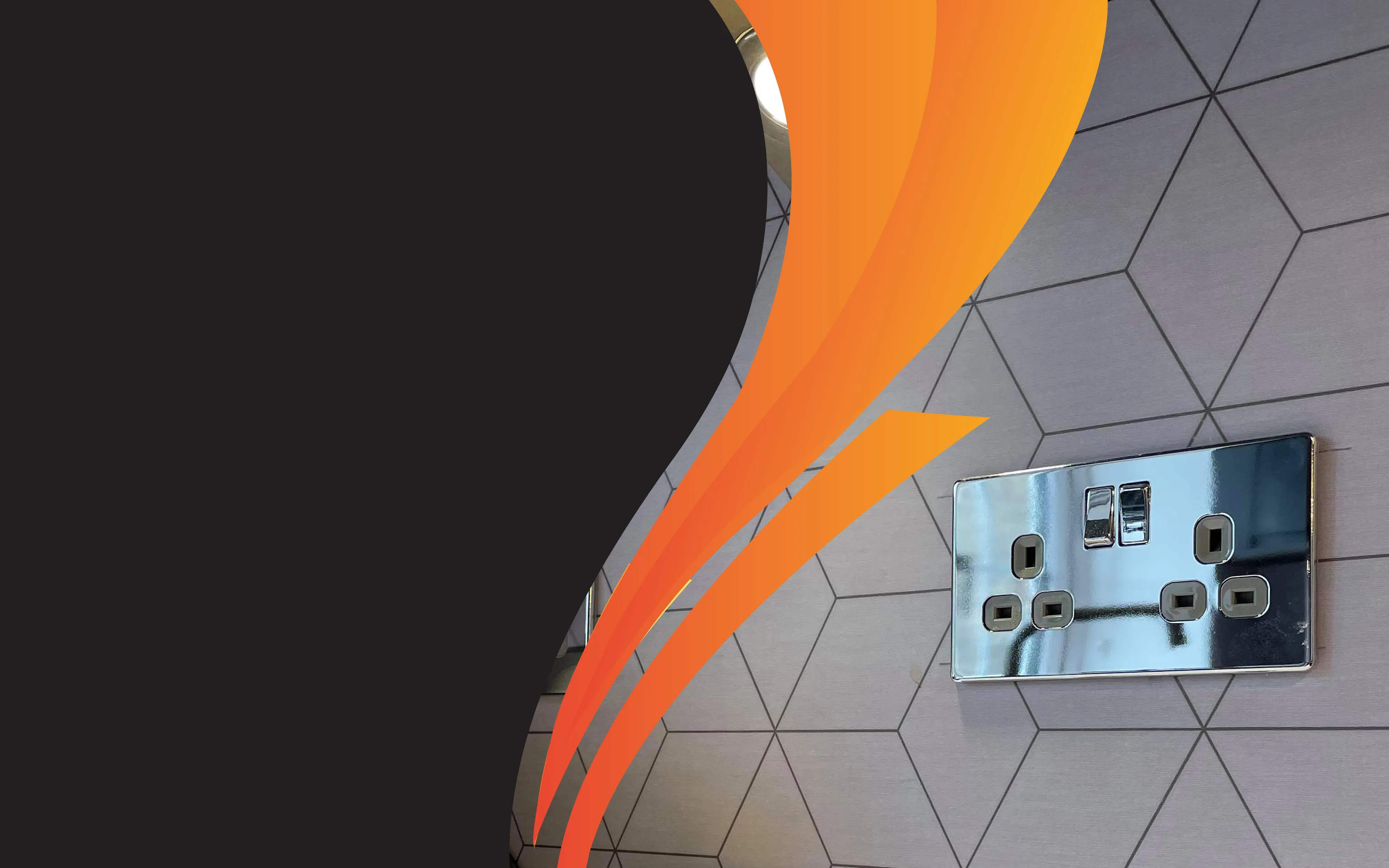 A chrome double socket on a hexagonal-tiled wall, with the Gilfoyle Electrical orange swoosh